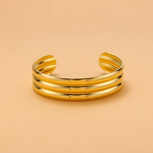 Macro detail of gold-plated titanium steel cuff bracelet featuring triple-row ribbed texture