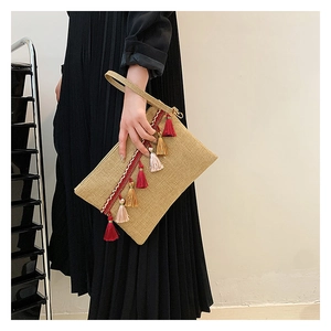 Straw envelope clutch bag detail featuring colorful tassels and ethnic woven webbing
