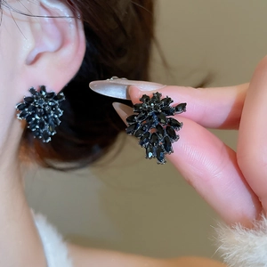 Close-up of black crystal cluster earrings with dark metal setting on ear