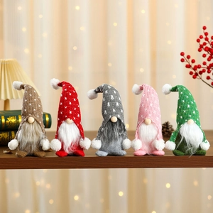 Set of five colorful knitted Christmas gnomes with polka dot hats on a wooden shelf