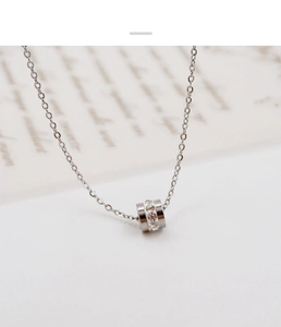 Detail of silver cylinder pendant with cubic zirconia on a delicate cross chain