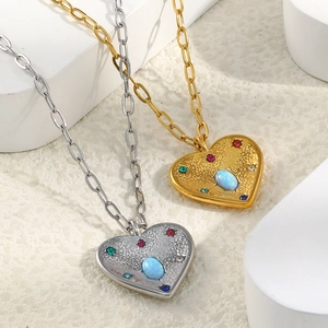 Détail de pendentifs cœur en or et argent avec texture martelée et opale bleue