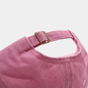 Detail of pink washed cotton baseball cap featuring an adjustable bronze metal buckle strap