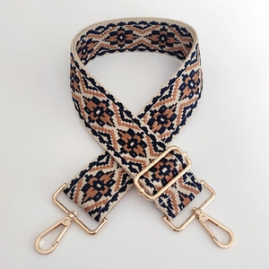 Close-up of geometric jacquard wide strap with gold-tone hardware and lobster clasps