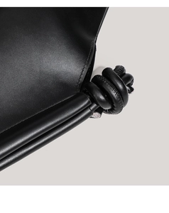 Macro shot of the black leather shoulder strap with a decorative knot and fine stitching