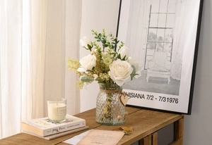 Detailed view of artificial white roses and eucalyptus in a textured glass vase