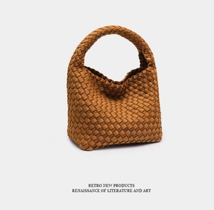 Detail of a brown woven bucket bag with thick leather texture and retro hobo silhouette
