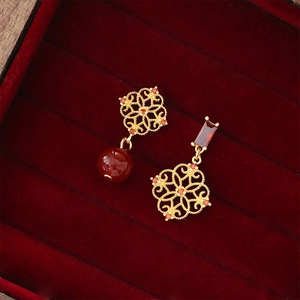 Detail of red zircon flower earrings in gold filigree inside a velvet jewelry box