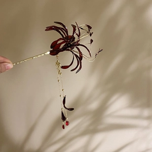 Detail of red Lycoris flower hair stick with golden tassel and vintage resin petals