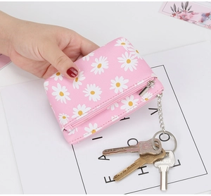 Close-up of pink daisy coin purse with cross-grain texture, silver zipper and keychain hook