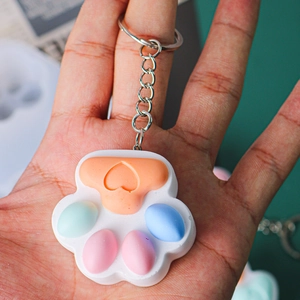 Close-up of hand holding a colorful cat paw fidget toy keychain with silicone buttons
