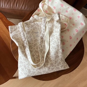Detailed view of floral cotton tote bags in beige and yellow on a wooden table