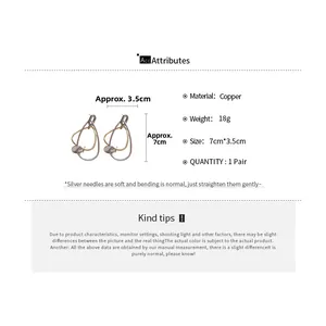 Détail de boucles d'oreilles gouttes géométriques en cuivre avec finition or et argent
