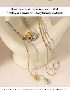 Detailed close-up of gold and silver oval pendant necklaces on a ceramic hand display