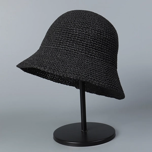Detail of hand-crocheted black straw bucket hat with textured weave on a display stand