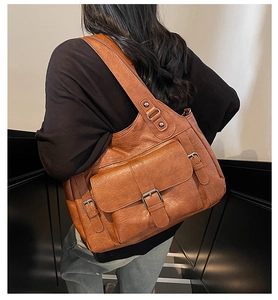 Brown leather tote bag featuring a front flap pocket with decorative buckle detail