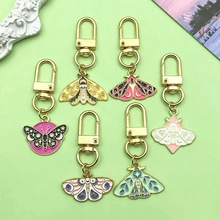 Macro detail of seven colorful moth and butterfly enamel keychains with gold lobster clasps
