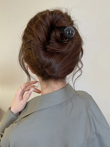 Détail d'un pic à cheveux à perle noire fixant un chignon élégant de style minimaliste
