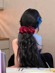 Détail d'une pince à cheveux avec fleurs en tissu bordeaux portée par une femme