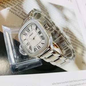 Macro detail of a silver square watch with Roman numerals and stainless steel strap