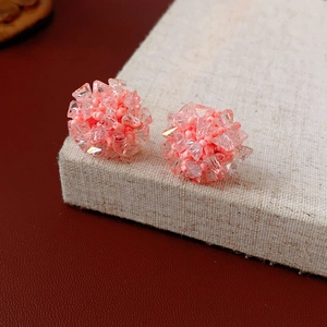 Macro shot of pink beaded cluster earrings on beige linen with a deep red backdrop