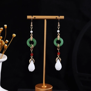 Detail of tassel earrings with green jade rings, pearls and golden butterfly hooks