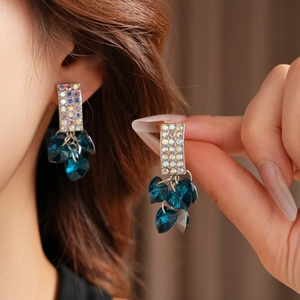 Close-up of blue heart crystal earrings with sparkling rectangular diamond accents
