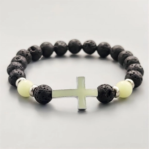 Makroaufnahme von schwarzen Vulkansteinperlen mit Leuchtkreuz und Silbertrennern