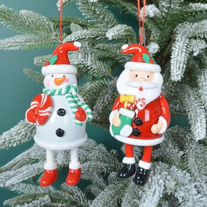 3D polymer clay Santa and Snowman ornaments hanging on a snowy Christmas tree