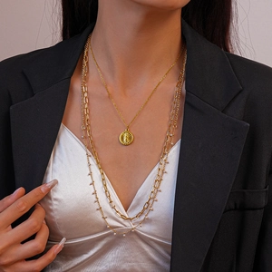 Detailed close-up of 18K gold-plated layered necklace with coin pendant and paperclip chain