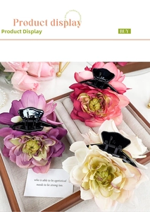 Three 3D fabric rose hair claws in purple, pink, and beige displayed on a jewelry tray