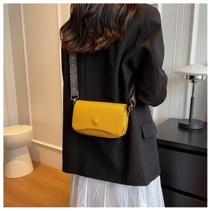Close-up of yellow lychee leather shoulder bag with a colorful patterned wide strap