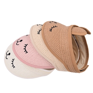 Detail of straw sun visors featuring cat eyelash embroidery and adjustable velcro straps