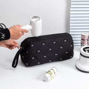 Detail of black quilted hair dryer storage bag with white bow pattern and zipper closure