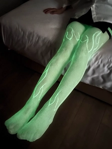 Gros plan de bas résille vert fluo avec des motifs de flammes blanches dans le noir