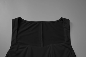 Detail view of the square neckline and vertical seam on a black slim-fit evening dress