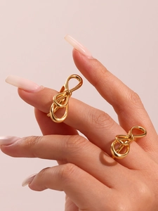 Close-up of golden geometric bow ring with elegant twisted lines on a model hand
