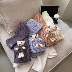 Sciarpe in maglia grossa con decorazione orso in quattro colori su un divano
