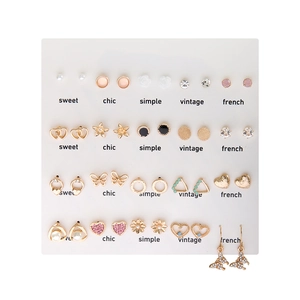 Detailed set of 20 pairs of gold earrings with pearls and crystals on a white display card