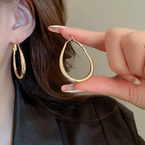 Close-up of polished gold teardrop earrings worn by a model for a chic luxury look