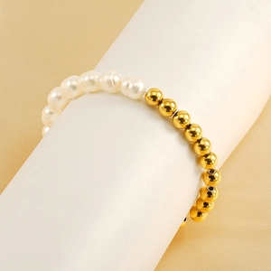Minimalist baroque pearl and gold bead spliced bracelet on a cylindrical stand