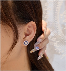Macro close-up of Evil Eye stud earrings with blue and white crystals on ear
