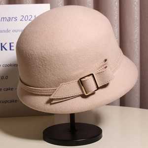 Détail d'un chapeau cloche en laine avec nœud élégant et boucle dorée sur un support
