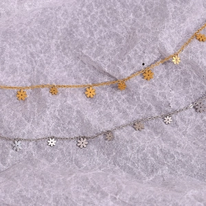 Detail view of dainty daisy charm necklaces in polished gold and silver finishes