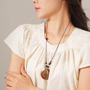Détail du collier en bois avec feuille métallique sur pendentif rond marron style Zen