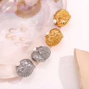 Detail of shell-shaped earrings in gold and silver finish with white pearls and water drops