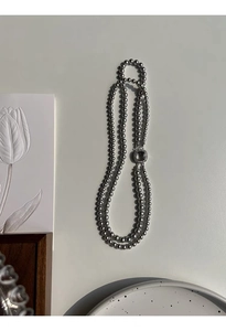 Detail of grey glass pearl double-layer necklace with micro-pave square shell clasp