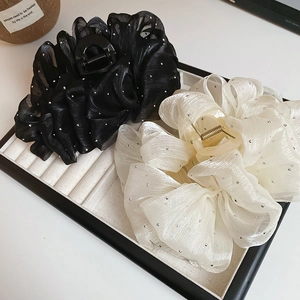 Detail of black and beige organza hair claws with shimmering rhinestones and soft pleats
