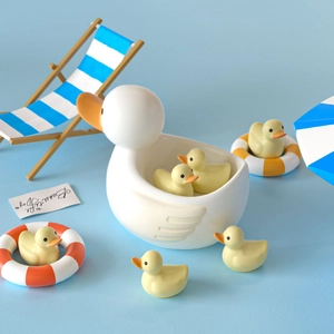 Detail of white duck shaped storage bowl with small yellow ducklings on beach backdrop