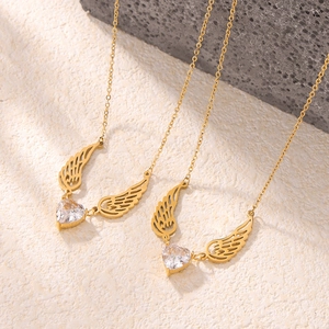 Golden heart wing necklace with white zircon pendant on natural stone background